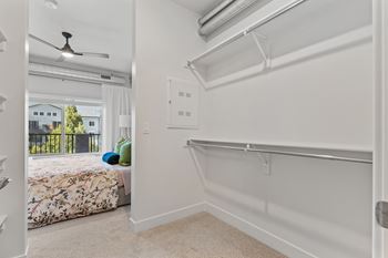 A white bedroom with a bed, a window, a fan, and a chair.